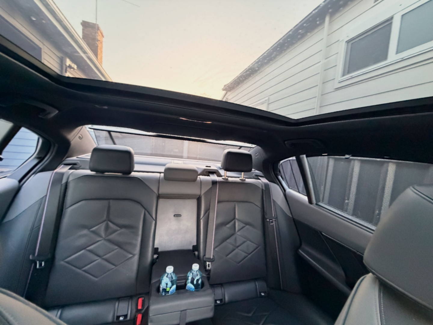 The rear cabin of the OSPIPO sedan showing the ventilated leather bench seat and rear climate controls